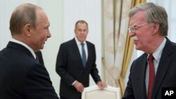 Russian President Vladimir Putin, left, and U.S. National security adviser John Bolton greet each other as Russian Foreign Minister Sergey Lavrov, center, looks on during the meeting in the Kremlin in Moscow, Russia, June 27, 2018. 