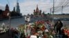 FILE - A man walks past flowers at the site where Kremlin critic Boris Nemtsov was murdered on Feb 27, 2015, at the Bolshoi Moskvoretsky Bridge, with St. Basil's Cathedral seen in the background, in central Moscow, Russia, March 6, 2015.