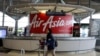 FILE - A woman walks past an AirAsia counter at Kuala Lumpur International Airport in Sepang, Malaysia, July 22, 2019. 