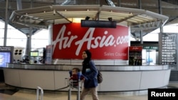 FILE - A woman walks past an AirAsia counter at Kuala Lumpur International Airport in Sepang, Malaysia, July 22, 2019. 