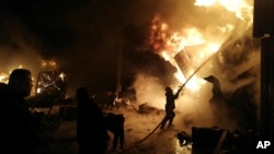 Vatrogasci gase požar na kontejnerima nakon raketnog napada, u pomorskoj luci u gradu Latakija, 28. decembra 2021, na fotografiji koju je objavila sirijska državna agencija SANA.