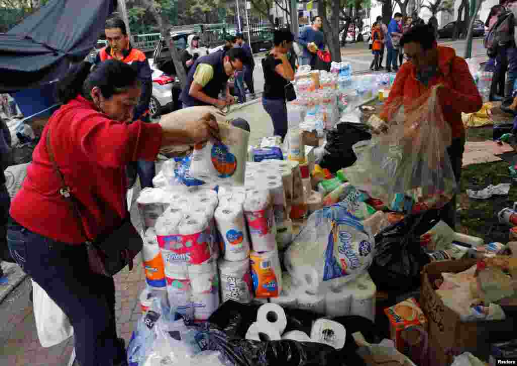 Residents remove donations of water bottles and items on the street next to a collapsed building in Mexico City, Sept. 20, 2017.
