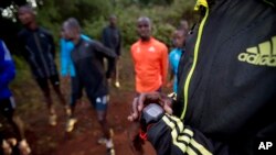 FILE - an athlete sets the timer on his watch before starting to run with others in Kaptagat Forest in western Kenya. 