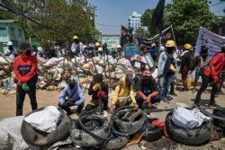 Protesters are seen gathered by a barricade during a crackdown by security forces on demonstrations against the military coup, in Yangon, Myanmar, March 20, 2021.