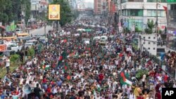Mahasiswa dan aktivis membawa bendera Bangladesh dalam pawai protes oleh Students Against Discrimination untuk memperingati satu bulan pengunduran diri mantan Perdana Menteri Sheikh Hasina , Dhaka, 5 September 2024. (Foto: AP)
