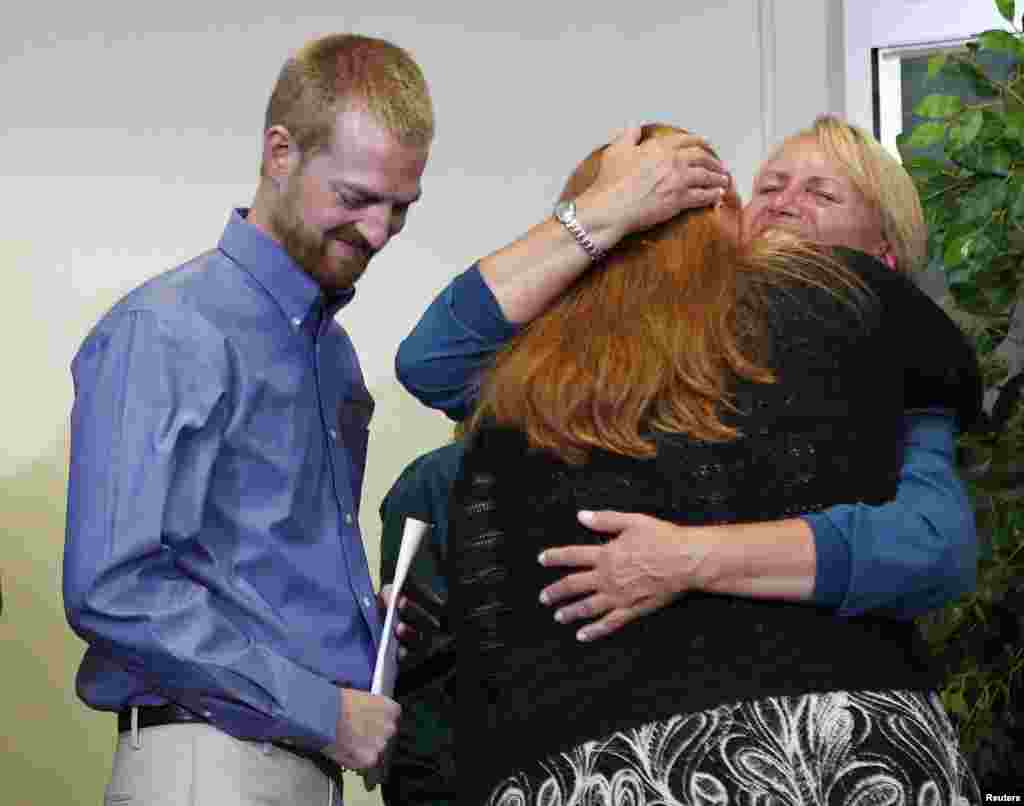 Kevin Brantly (left), who contracted the deadly Ebola virus, looks down as his wife Amber (center) hugs a member of Emory&#39;s medical staff during a press conference at Emory University Hospital in Atlanta, Georgia, Aug. 21, 2014.