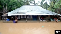 Residents take shelter under a house roof in the Paquite district of Pemba, April 29, 2019, as Cyclone Kenneth hit northern Mozambique.