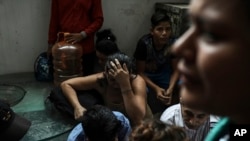 Detained migrants stand together in a storage room at the back of the Azteca Hotel where they tried to hide from Mexican immigration agents conducting a raid in Veracruz, Mexico, June 27, 2019.