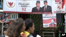 A couple rides a motorcycle past a campaign banners for Indonesian presidential candidate Prabowo Subianto, left, and running mate Sandiaga Uno in Jakarta, Indonesia, Jan. 17, 2019. (AP Photo/Achmad Ibrahim)