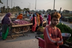 FILE - Vendors and customers are seen without masks at a market on the outskirts of New Delhi, India, Nov. 20, 2020.