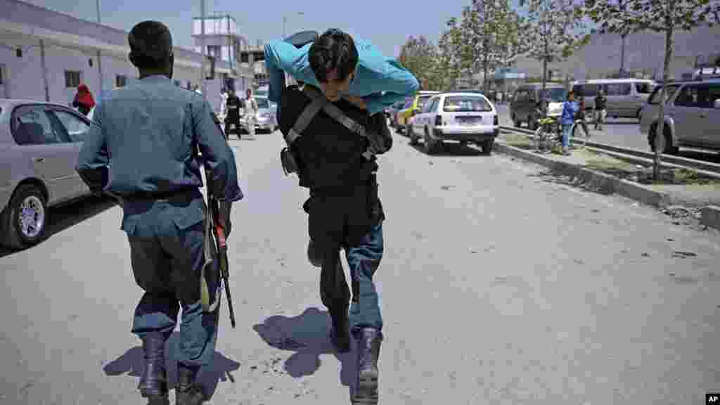 An Afghan policeman carries a wounded man at the site of a suicide attack in Kabul, Afghanistan, Aug. 10, 2014. 