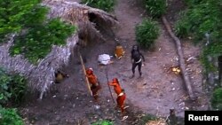 FILE - Members of an uncontacted Amazon Basin tribe and their dwellings are seen during a flight over the Brazilian state of Acre along the border with Peru in this May, 2008 photo distributed by FUNAI.
