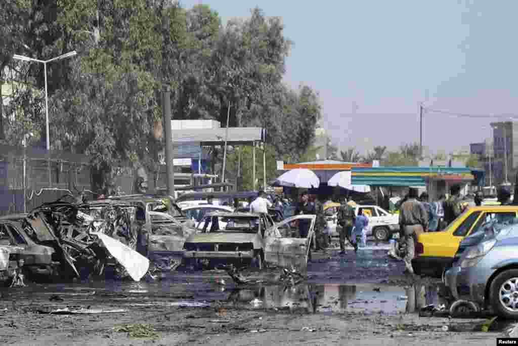 Iraqi security forces inspect damaged vehicles after a bomb attack in Baghdad&#39;s Kadhimiyah district, August 15, 2013. 