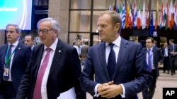 Presiden Komisi Eropa, Jean-Claude Juncker (tengah kiri) dan Presiden Dewan Eropa, Donald Tusk (tengah kanan) berjalan melalui atrium di sela pertemuan tingkat tinggi Uni Eropa di Brussels, 19 Oktober 2017.