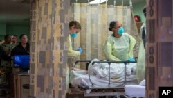 In this March 29, 2020 photo provided by the U.S. Navy, medical personnel assigned to the hospital ship USNS Mercy docked at the Port of Los Angeles treat a non-COVID-19 patient from a Los Angeles-area medical facility.