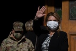 Bolivia's interim President Jeanine Anez, wearing a face mask to help curb the spread of the new coronavirus, waves during a procession Corpus Christi, in La Paz, Bolivia, June 11, 2020.