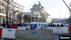 FILE - People walk beside concrete barriers at the Brandenburg Gate, ahead of the upcoming New Year's Eve celebrations in Berlin, Dec. 27, 2016. 