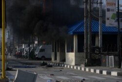 People stand near a burning shop as demonstrators protest against police brutality in Lagos, Nigeria, Oct. 21, 2020.