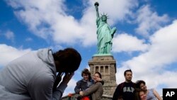 Para wisatawan yang mengunjungi New York hari Minggu (13/10), bisa kembali berkunjung ke komplek Patung Liberty yang kembali dibuka. 