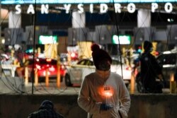 A woman holds a candle during a vigil in support of migrants as she stands at the entrance to the San Ysidro Port of Entry along the border between the United States and Mexico, Jan. 19, 2021.
