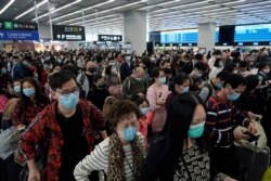 Passengers wear protective face masks at the departure hall of the high speed train station in Hong Kong, Jan. 23, 2020.