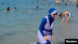 Une femme portant un burkini marche dans l'eau le 27 août 2016 sur une plage à Marseille en France.