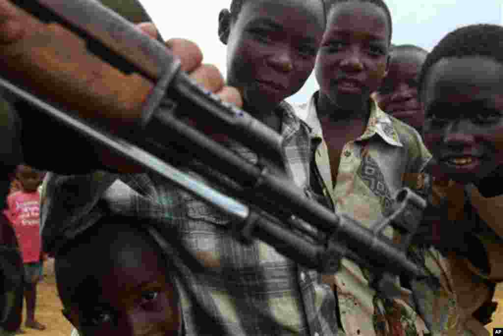 Des enfants s&#39;approchent d&#39;un homme armé en RDC. Au Congo, des dizaines d&#39;enfants abandonnés dans la rue, sont exposés aux armes et sont parmi les premières vicitimes des bavures policières dénoncées. (AP Photo/John Bombengo). 