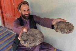 Seorang petani berusia 37 tahun, Mohaiyudeen, memamerkan paket opium setelah memanennya dari ladang opiumnya di distrik Surkh-Rod, Provinsi Nangarhar, Afghanistan, 28 Juni 2020. (Foto: AFP)