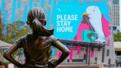Patung Gadis Pemberani (The Fearless Girl) memandang pesan "Please Stay Home" di Federation Square yang sepi pada hari pertama 'lockdown' di Melbourne, Australia, 13 Februari 2021. (REUTERS/Sandra Sanders)