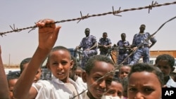 Des enfants réfugiés érythréens observent la patrouille de l'armée en arrière-plan dans le camp de réfugiés de Wad Sherrife, près de Kassala, au Soudan. 
