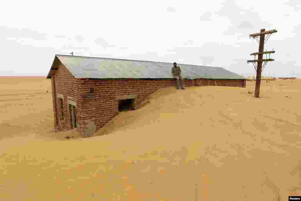 Seorang pekerja bersandar pada atap sebuah bangunan yang dikelilingi pasir akibat gangguan pada gurun pasir, di stasiun kereta api Ogrein di negara bagian Laut Merah, Sudan, 1 Agustus 2013. 