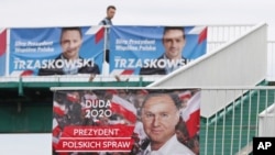 Seorang pria berjalan melintas di depan poster dua kandidat putaran kedua pilpres Polandia antara petahana Presiden Andrzej Duda dan saingannya Wali Kota Warsawa Rafal Trzaskowsk, Sabtu, 12 Juli 2020.