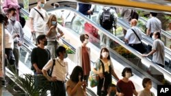 មនុស្ស​ម្នាពាក់ម៉ាស់​ការពារ​ឆ្លង​វីរុស​កូរ៉ូណាឡើងជណ្តើរយន្ត​នៅស្ថានីយ Yokohama ក្បែរ​ទីក្រុង​តូក្យូកាលពី​ថ្ងៃទី២២​ កក្កដា ឆ្នាំ២០២០។