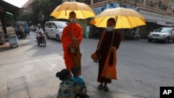 រូបឯកសារ៖ ព្រះសង្ឃដែលមានពាក់ម៉ាស់ដើម្បីការពារការឆ្លងជំងឺកូវីដ១៩ និមន្តបិណ្ឌបាត្រនៅរាជធានីភ្នំពេញ កាលពីថ្ងៃទី៦ ខែកុម្ភៈ ឆ្នាំ២០២១។