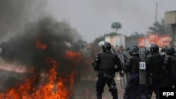 Des policiers congolais battent en retraite devant un cocktail Molotov lancé en leur direction à la périphérie de Kinshasa, République Démocratique du Congo, 25 juillet 2006. EPA / NIC Bothma