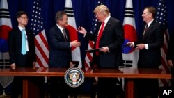 FILE - President Donald Trump hands a pen to South Korean President Moon Jae-In during a signing ceremony for the United States-Korea Free Trade Agreement during the U.N. General Assembly, Sept. 24, 2018, in New York. 