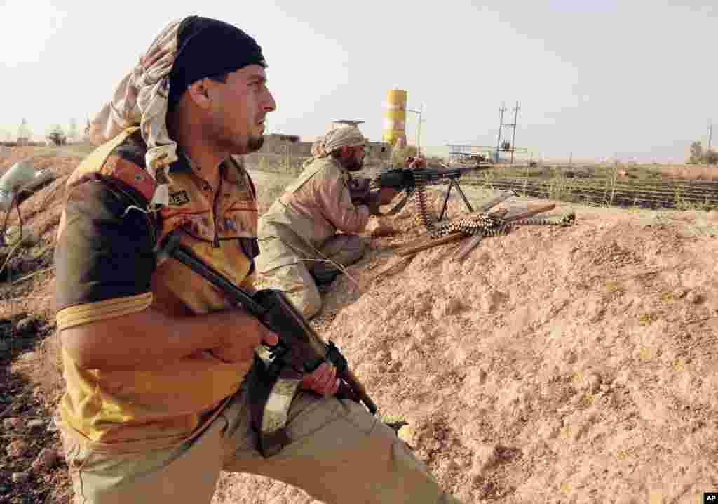 Fighters with the &quot;Peace Brigades&quot; hold their weapons in combat position on the outskirts of Samarra, Iraq, July, 2014.