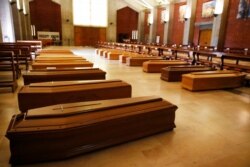 FILE - Coffins with coronavirus victims to be transferred to a crematorium are lined up on the floor of San Giuseppe church in Seriate, one of the areas worst hit by the coronavirus, near Bergamo, Italy, March 26, 2020.