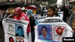 FILE - Relatives and friends hold banners with images of some of the 43 missing students of Ayotzinapa College Raul Isidro Burgos as they march in Mexico City to mark the first anniversary of the students' disappearance, Sept. 26, 2015.