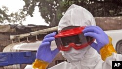 Petugas kesehatan Liberia memakai alat pelindung sebelum memindahkan jenazah pria yang diyakini mati karena Ebola di Monrovia (29/8). (AP/Abbas Dulleh)