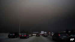 Traffic makes its way south on I-15 as ash from fires fills the air on Aug. 9, 2018 in Lake Elsinore, Calif. 