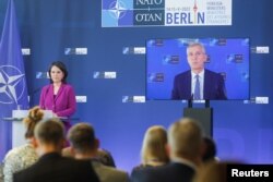 German Foreign Minister Annalena Baerbock, stands next to NATO Secretary General, Jens Stoltenberg, seen on a screen speaking during a news conference at a NATO meeting in Berlin, Germany May 15, 2022. (REUTERS/Michele Tantussi)