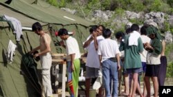FILE - Men shave, brush their teeth and prepare for the day at a refugee camp on the Island of Nauru, Sept. 21, 2001.