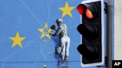 A view of the Banksy Brexit mural of a man chipping away at the EU flag in Dover, England, Tuesday, Dec. 11, 2018. 