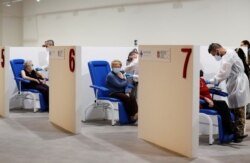 FILE - Women receive the Moderna vaccine against the coronavirus disease at the Music Auditorium in Rome, Italy, April 14, 2021.