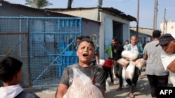 2023年10月28日，在代尔巴拉赫，巴勒斯坦人涌入联合国运营的一个援助供应中心，该中心向流离失所的家庭分发食品，此前以色列呼吁加沙北部100多万居民向南迁移，以确保安全.(法新社)