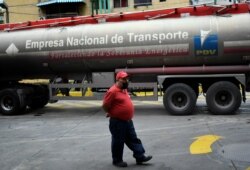 A worker wearing a face mask to protect against the coronavirus waits while a tanker truck fills the gasoline reservoir of a state oil company gas station, in Caracas, Venezuela, May 31, 2020.