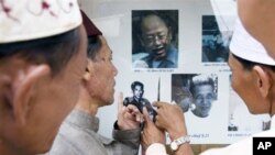 Khmer Islam men pointing at photos of former Khmer Rouge leaders, in Tuol Sleng museum. 