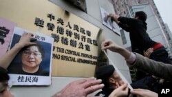 FILE - Activists paste photos of missing booksellers, one of which shows Gui Minhai at left, during a protest outside the Liaison Office of the Central People's Government in Hong Kong, Jan. 3, 2016.