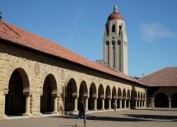 FILE- People walk on the Stanford University campus beneath Hoover Tower in Stanford, Calif., March 14, 2019.